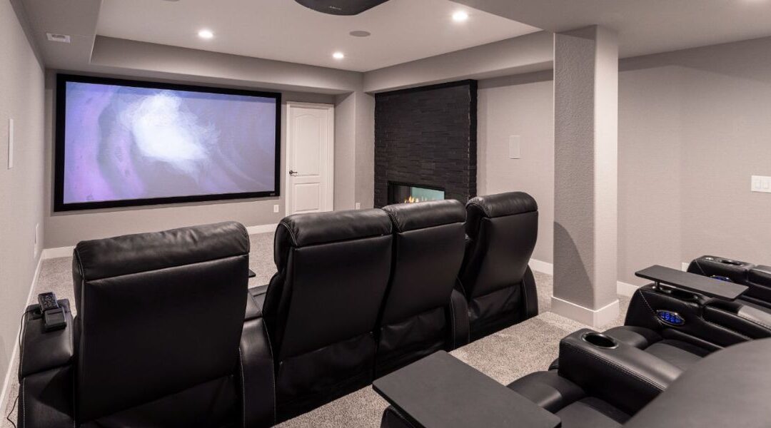 Luxury basement finishing in South Jordan UT showcasing a high-end home theater with acoustic paneling, stadium plush seating, and smart lighting.